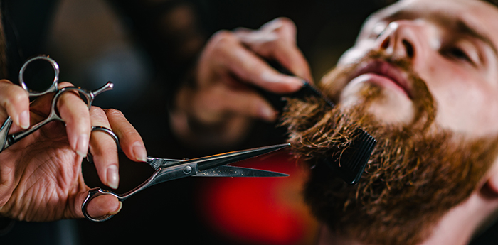 Barbershop, young man having a beard trimming