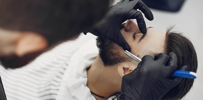 Man with a beard. Hairdresser with a client. Brunette in a barbershop